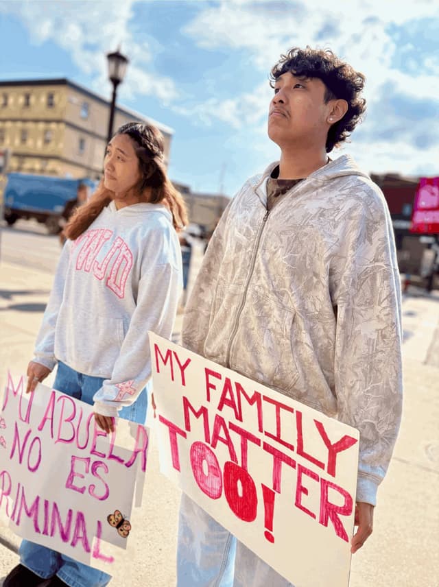 Demonstrators holding signs reading 'My family matters too' and 'Mi abuela no es criminal'